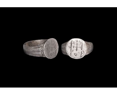 6th-7th century AD. A silver finger ring with flat-section hoop, arcade to the shoulders, discoid bezel with cross crosslet a