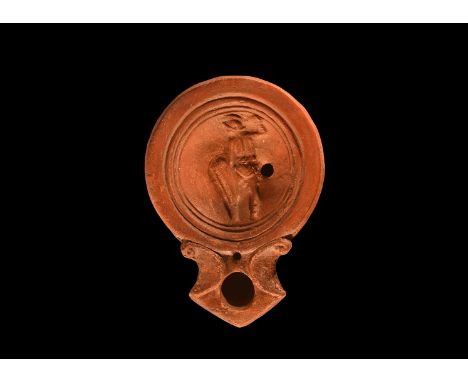 1st-2nd century AD. A squat terracotta oil lamp with volute scrolls to the nozzle, broad recessed discus with standing murmil