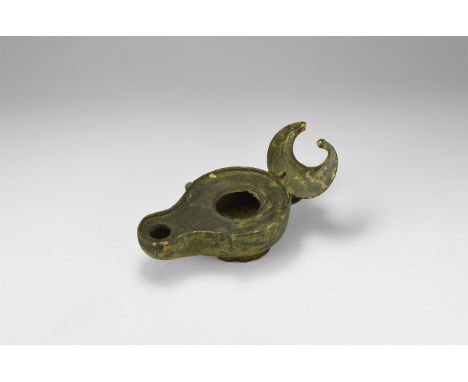 6th-7th century AD. A bronze lamp with flared base, D-section bowl and nozzle, raised rim to the flat upper face, two pierced