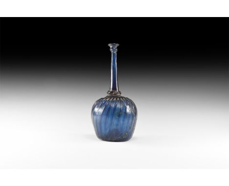 17th-18th century AD. A blue glass flask with bulbous body and tall neck; the body with dimple base and raised radiating band
