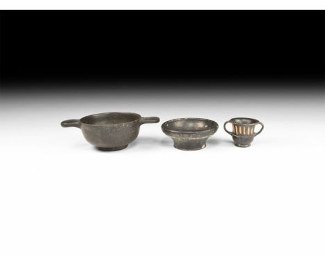 5th-3rd century BC. A group of blackware ceramic containers comprising: a footed bowl with carinated rim; a miniature bell kr