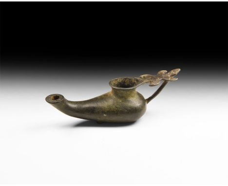 6th-8th century AD. A bronze oil lamp with bulbous body, tapering rounded nozzle with discoid vent, raised and flared rim to 