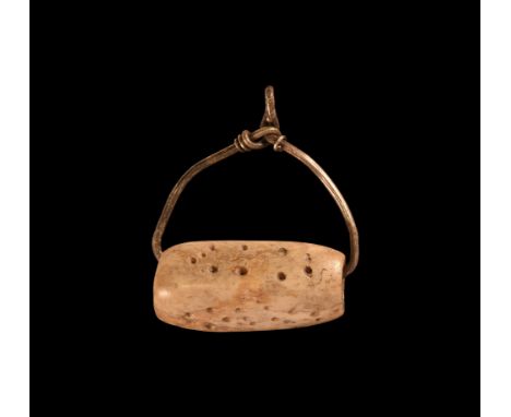 9th-11th century AD. An amuletic pendant comprising a square-section bone bead with pointillé detailing mounted on a silver w