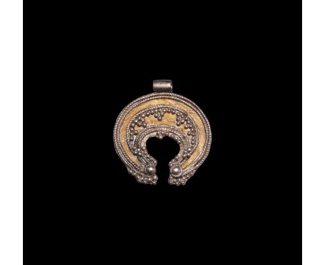 9th-12th century AD. A parcel-gilt silver pendant comprising a crescent plaque with applied filigree bands and granule cluste
