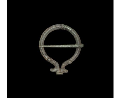 1st century AD. A flat-section penannular brooch with knops flanking the slot, T-shaped finial, coiled pin.   15 grams, 53mm 