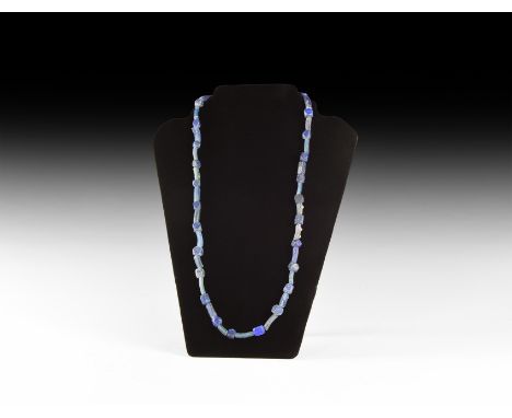1st millennium BC. A restrung necklace of cornerless cube shaped lapis lazuli beads alternating with tubular blue glass beads