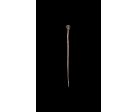6th-7th century AD. A silver dress pin with tapering shank, polyhedral head with incised lozenge motifs, cross to the upper f