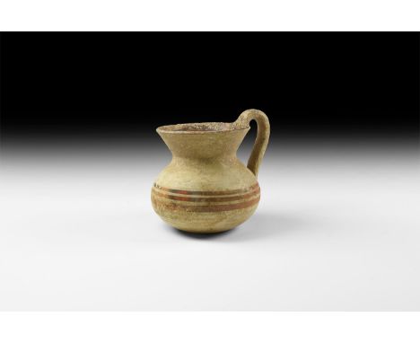 5th-3rd century AD. A squat burnished ceramic jar with conical mouth, strap handle, painted concentric bands in brown and och