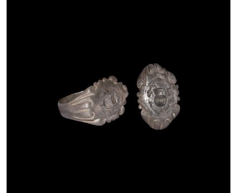 3rd century AD. A silver-gilt finger ring with narrow hoop, flared shoulders with segmented panels extending to scrolled bord