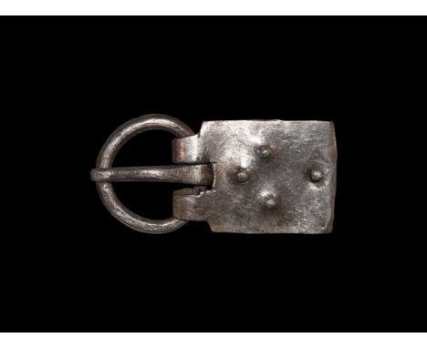 6th century AD. A large silver buckle comprising a round-section loop, curved tongue with tip resting on the loop, rectangula