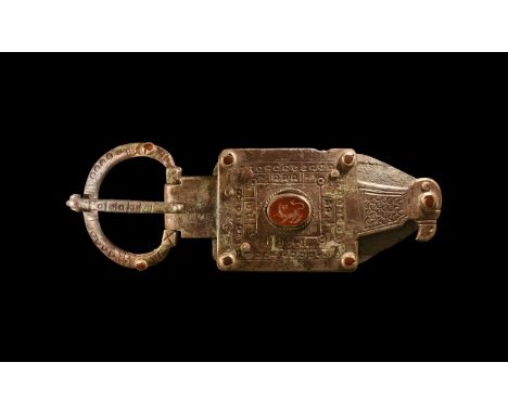 5th-6th century AD. A silver buckle comprising: flat annular loop with hatching, punched annulets, two cabochon garnets in ce