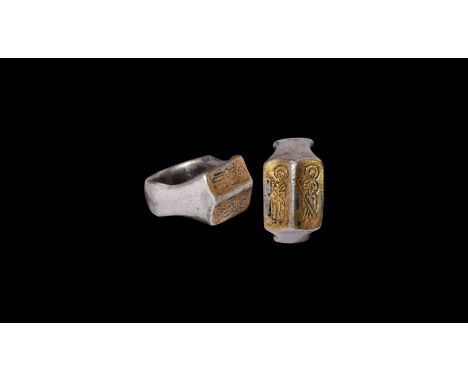 15th century AD. A silver-gilt finger ring with broad hoop, scooped shoulders, facetted rectangular bezel with images: on the