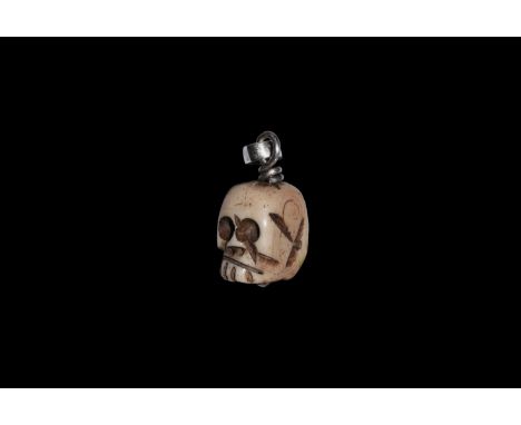 17th century AD. A bone pendant of a skull, engraved details to the face; twisted silver wire through, with suspension ring. 