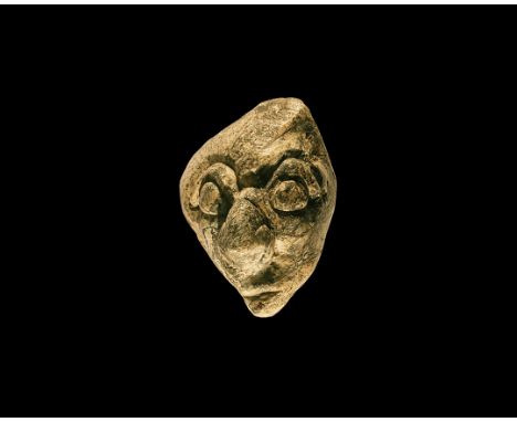 Pliocene Period, 5.2-2.5 million years BP. A mastodon fossil bone carving depicting a human face with prominent eyes, nose an