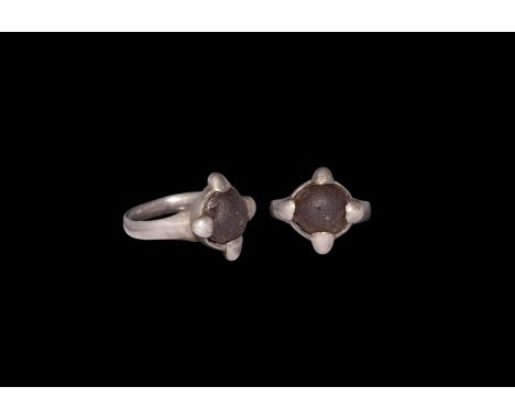 9th-11th century AD. A silver finger ring comprising a D-section hoop, discoid bezel with radiating lobes, inset amber(?) cab