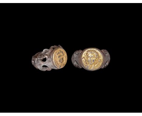 3rd century AD. A silver finger ring with D-section hoop, openwork scrolled borders, gilt discoid bezel with portrait bust. C