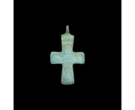 14th-15th century AD. A bronze cross pendant with low-relief nimbate robed figure in orans posture, blundered legend above '+