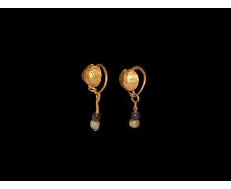1st century BC-1st century AD. A matched pair of gold earrings, each a domed disc with hook-and-eye fastener, dangle with lat