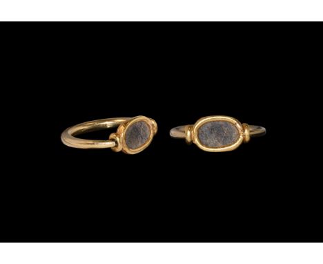 Ptolemaic Period, 332-30 BC. A gold finger ring comprising a substantial round-section hoop, pivoting plaque with inset lapis