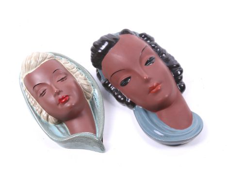 Two goldscheider terracotta masks. One with black hair the other with blonde, both with blue surround, L26cm. 