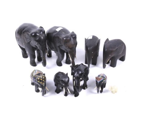 A large collection of eight wooden Elephants. A stained hardwood with bone tusks, along with a small jade example, max H16.5c