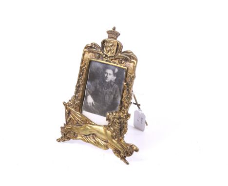 A brass easel photograph frame. In a military style showing a lion and coat of arms, sold with a photo of a soldier, H25cm. 