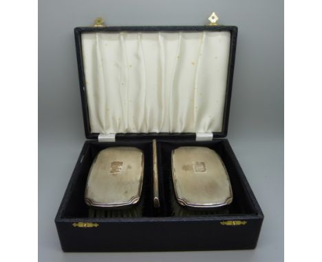 A pair of silver backed brushes and a comb, cased 