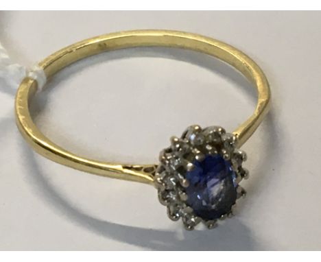 A gold band ring, unmarked with central sapphire and diamond surround. Ring size 6