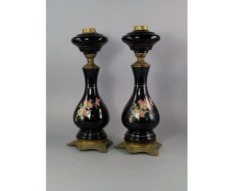 A pair of enamelled metal and gilt metal oil lamp bases, late 19th/early 20th century, with shaped reservoirs above bulbous b