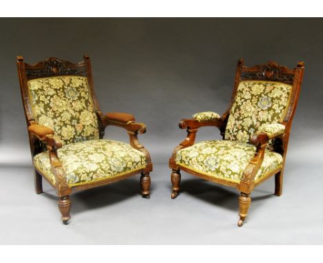 A pair of Edwardian oak armchairs, the top rails carved with vine and berry decoration, over stuffed tapestry seats, scrollin
