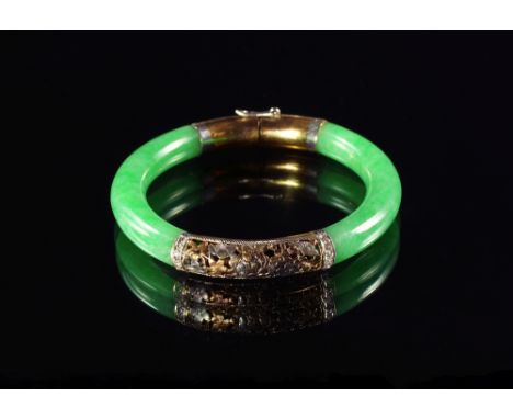A green jade bangle, 20th century, with yellow and white metal mounts, pierced with leaves and mounted with diamonds, 6.5cm d