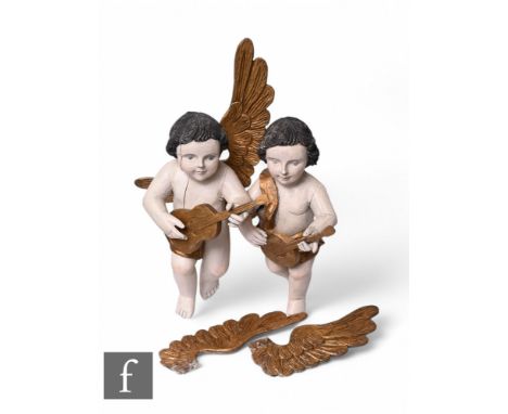A pair of 19th Century carved wood and overpainted angelic wall embellishments, each with open wings and playing a musical in