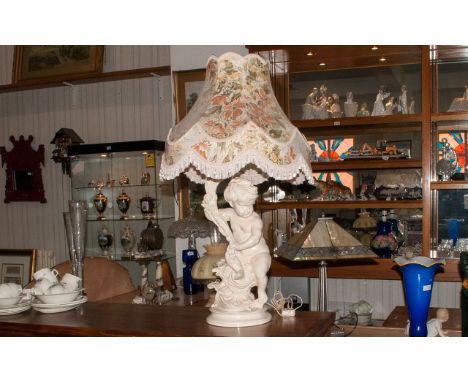 A Large Decorative Plaster Base Lamp in the form of a Putti holding a cornea copia, large floral shade and predominantly crea