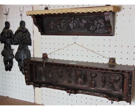 A carved mahogany wall bracket supporting three brass hooks with carved character detail within an egg and dart border, signe