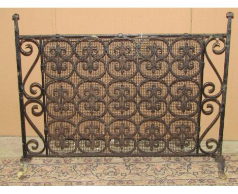 An iron work fire screen with repeating tied scroll panel, faceted finials and splayed flattened feet, 79cm wide x 60cm high 