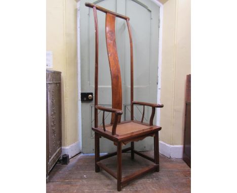 A Chinese throne chair in elm, raised on turned supports with wicker work seat and extended back with shaped splat and simple