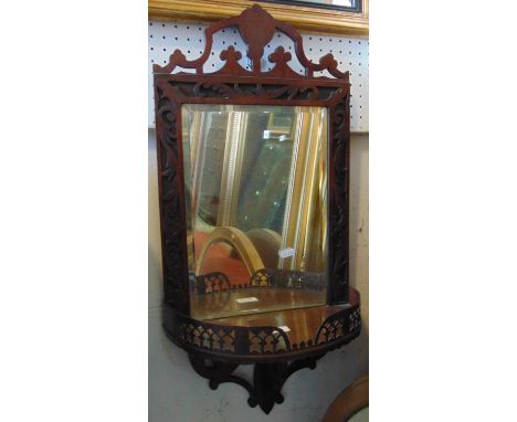 An Edwardian Chippendale revival wall shelf/bracket with pierced and blind fret detail, and enclosing a rectangular bevelled 