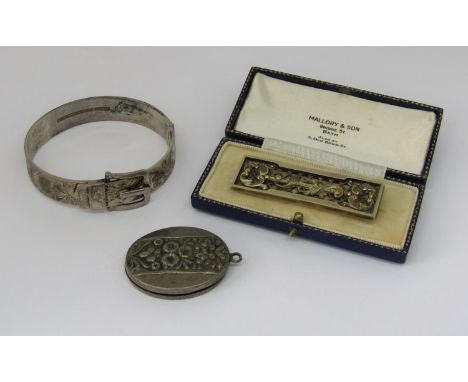 Silver hinged buckle bangle with engraved scrolled decoration, together with a rectangular silver brooch by Spencer &amp; Co,