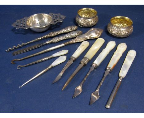 A mixed collection of silver comprising a twin handled strainer, pair of embossed table salts and various white metal handled