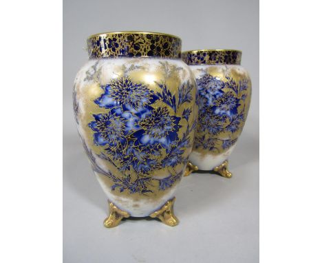 A pair of early 20th century Carltonware vases with painted blue and white and gilded floral sprays and prunus blossom border