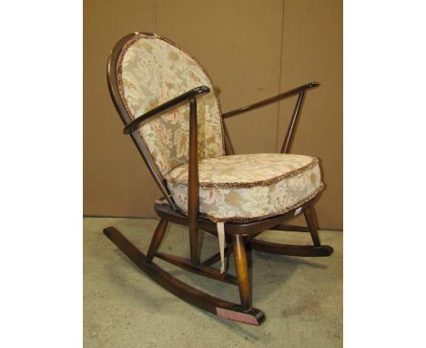 An Ercol elm and beechwood hoop and stick back low rocking chair with open arms and circular gold label, together with a furt