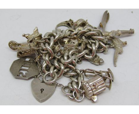 A silver charm Bracelet with heart padlock clasp fitted with various novelty charms to include a harp, the old lady who lived