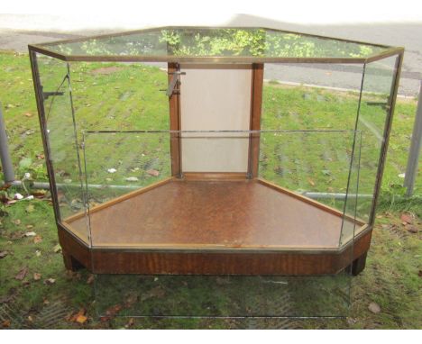 An art deco style floorstanding brass framed shop display cabinet with canted corners and glazed surround, enclosed by a sing