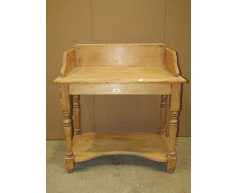 A stripped pine washstand with shallow raised three quarter shaped back, raised on turned supports united by an under tier/pl