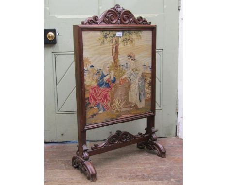 A mid-19th century mahogany framed fire screen, with carved and scrolled detail, enclosing a hand worked tapestry panel showi