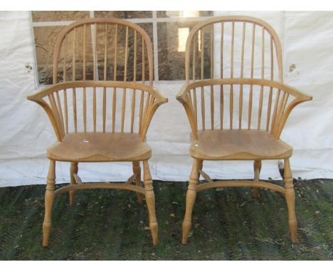 A pair of Windsor light ashwood hoop and stick back armchairs with saddle shaped seats raised on splayed turned and tapered s