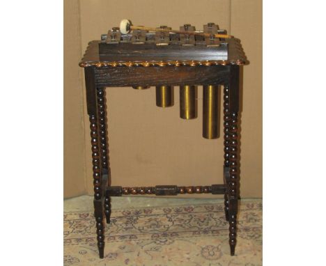 A glockenspiel with five graduated keys and tubes, raised on an oak stand/table of rectangular form with pie crust moulded ou