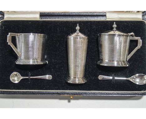 An Art Deco silver engine turned angular three piece cruet set, together with a salt and a mustard spoon, all with hallmarks 