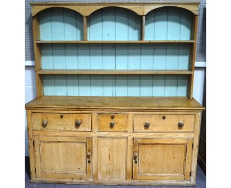 A Victorian pine kitchen dresser, the rack with three arched shelf sections, over three drawers and cupboard base, 183cm high