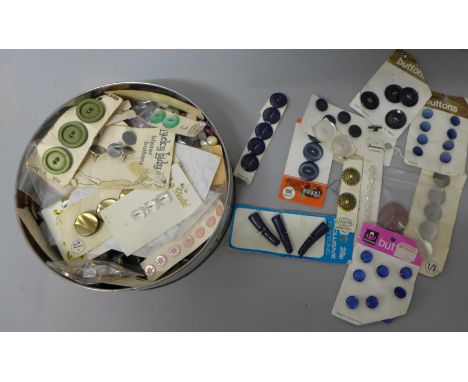 A tin of vintage buttons, many on original shop stock cards 